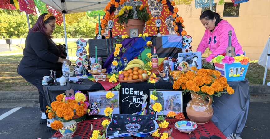 two volunteers who are women, setting up a Day of the Dead alter